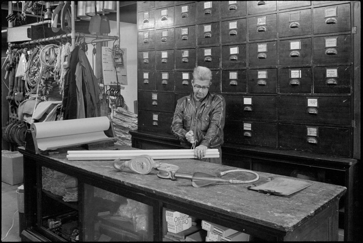 Interior view of Greek ship store Alex Callinicos & Co Ltd, George Street, Butetown, with assistant Mr Williams behind the counter.