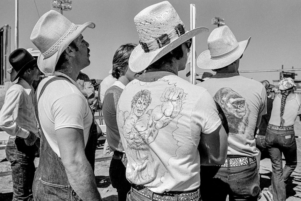 USA. ARIZONA. General.  Prescott's Frontier Days cowboy festival was the world's first rodeo and started in 1888.  Wild horse riding.  Spectators dress up as though competitors.  A picture of macho aggressiveness. 1980.