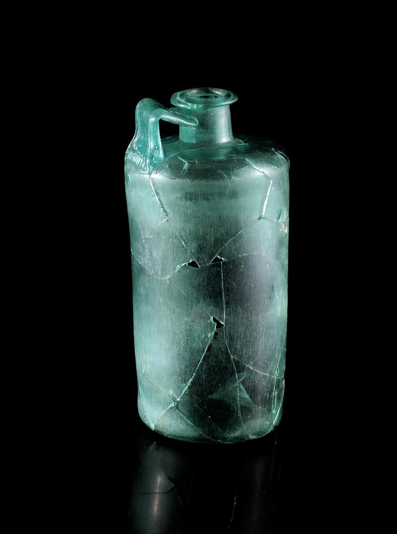 Roman cylindrical glass bottle - Caerleon, Vine Cottage.  1st century AD to early second.  Shows outer abrasion of the walls of the body of the vessel in zoom function.  The abrasion ends where the sides begin to curve and narrow approaching the  neck of the vessel.