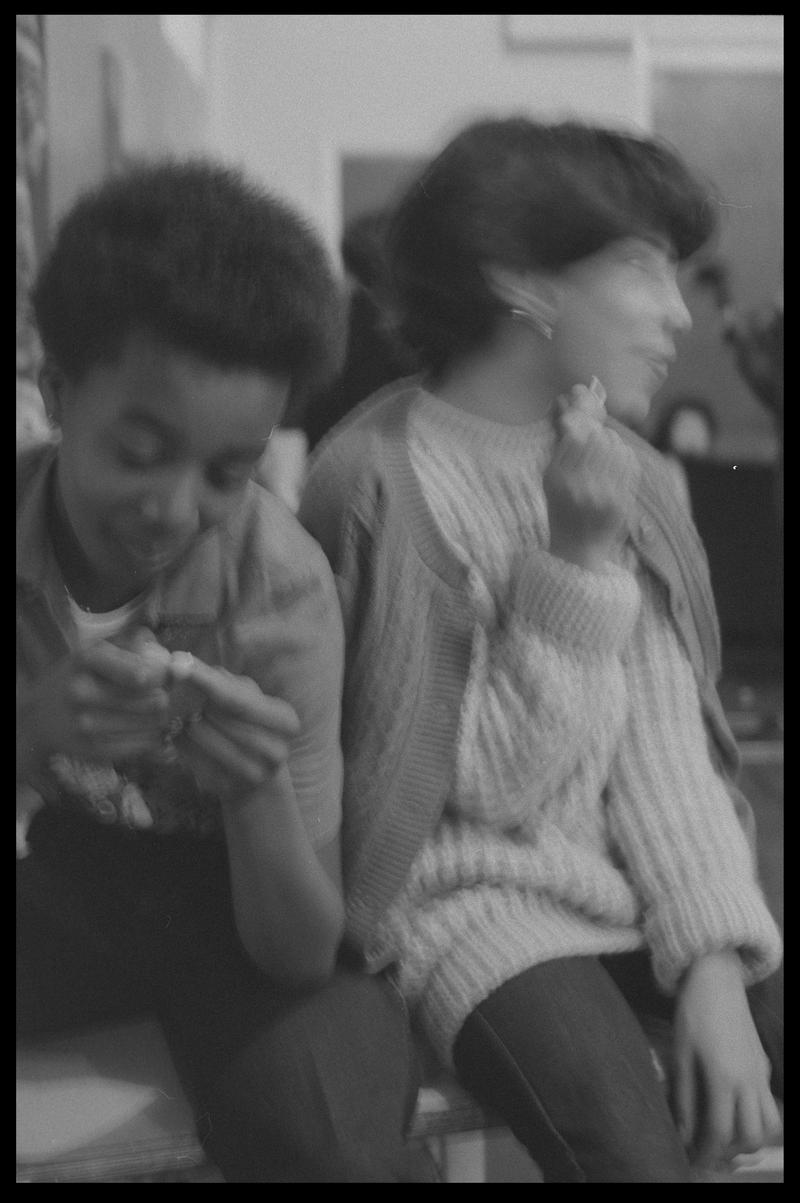 Two girls sat at side of hall in Butetown Youth Club.