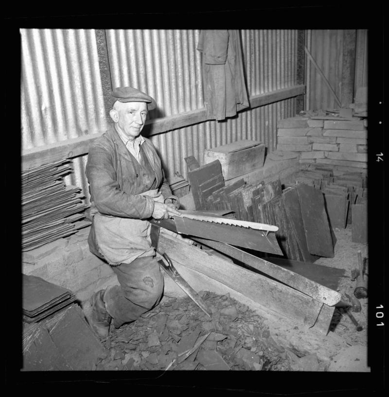 Quarryman using a measuring stick, 'pric mesur', to measure a piece of slate before it is dressed, Dinorwig Quarry, early 1960s.
