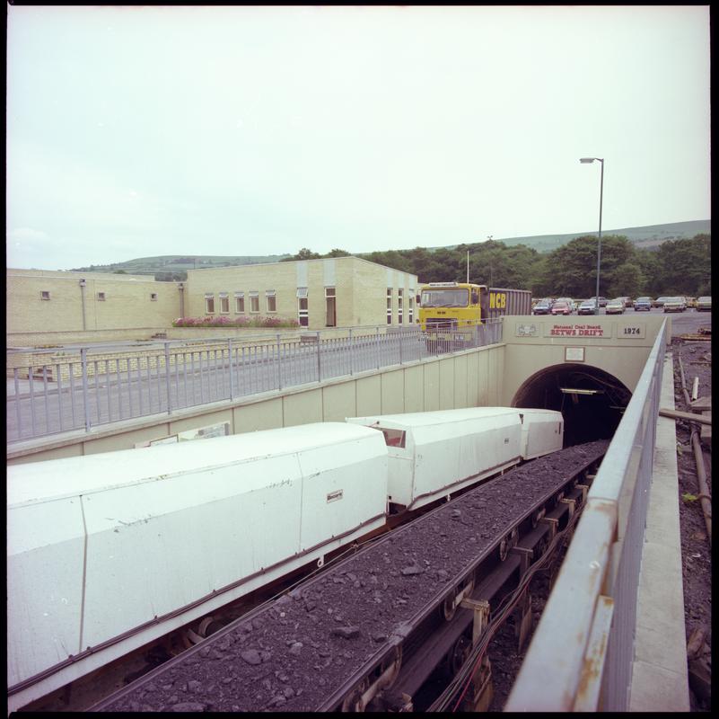 Colour film negative showing the entrance to the mine with man riding cars and conveyor, Betws Mine 10 June 1982.  '10 Jun 1982' is transcribed from original negative bag.  Appears to be identical to 2009.3/2178.