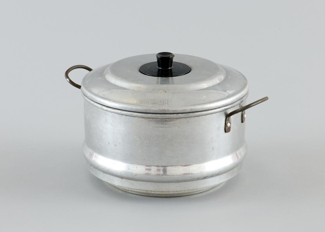 Aluminium steamer, complete with lid, two metal handles each side of the body. With paper label stuck to side.