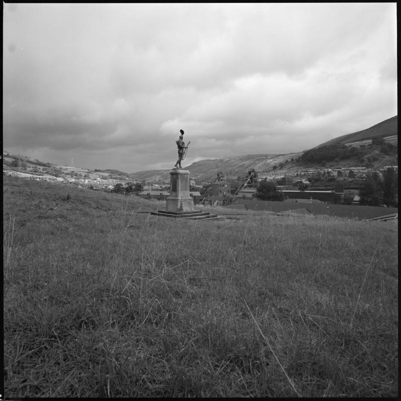 Black and white film negative showing a statue with Merthyr Vale Colliery in the background.