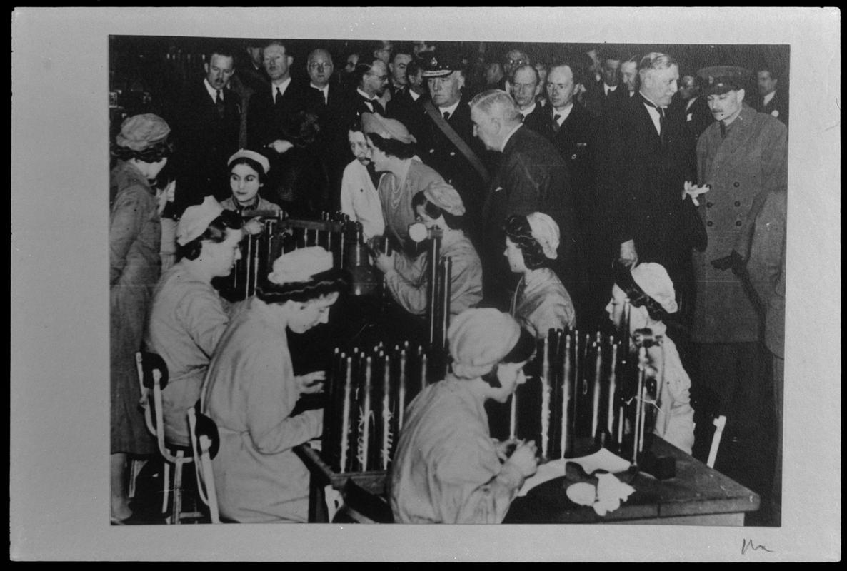 Film negative of a photograph showing visit of King George VI and Queen Elizabeth to Currans, Butetown during World War II. Staff are making shells.