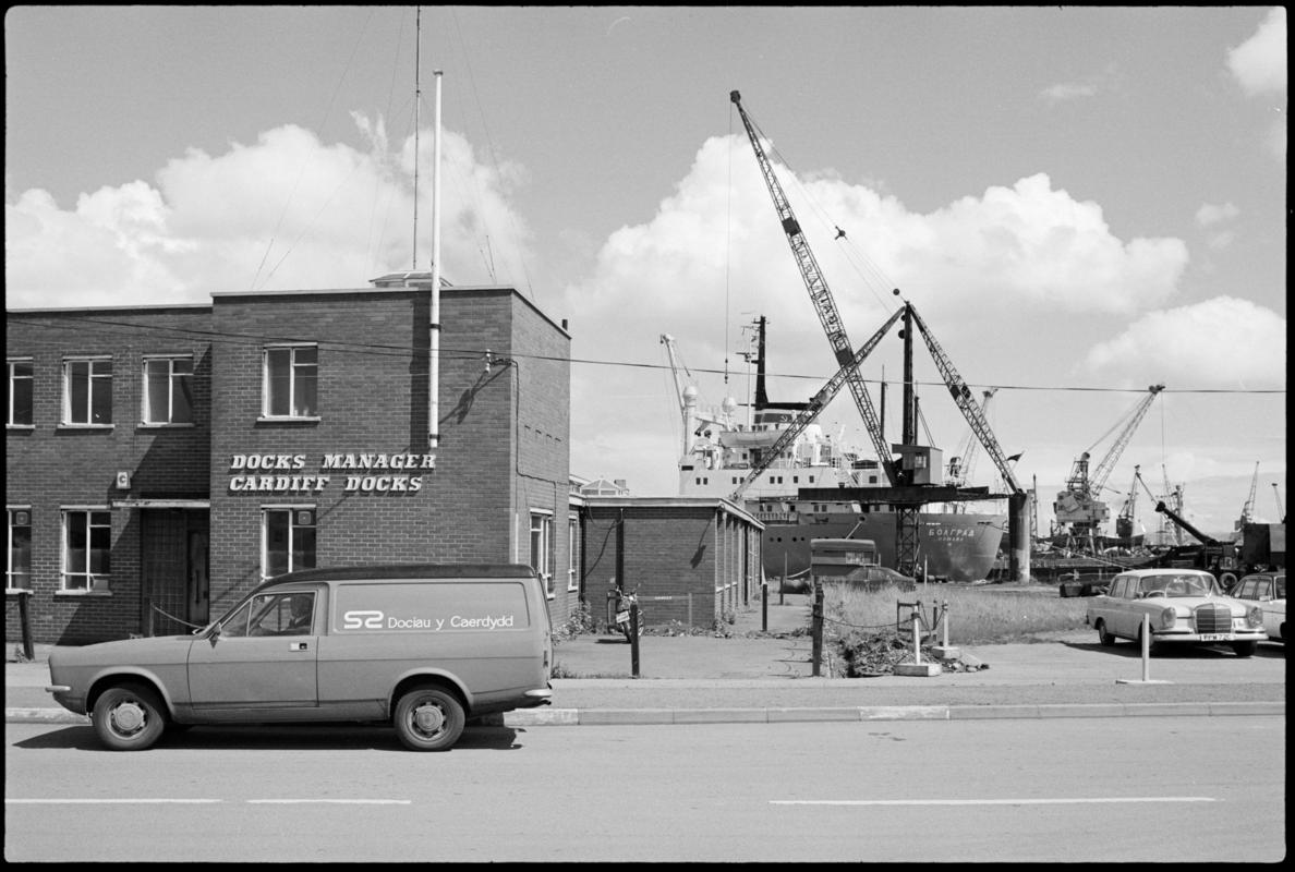 Exterior view of Cardiff Docks Manager's building with Cardiff Docks van parked outside and a Russian ship in dock in the background.