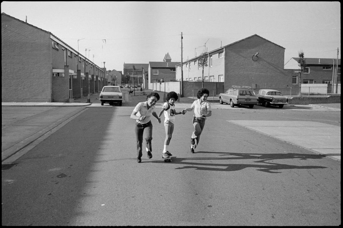 Three youngsters playing with a skateboard in Butetown.