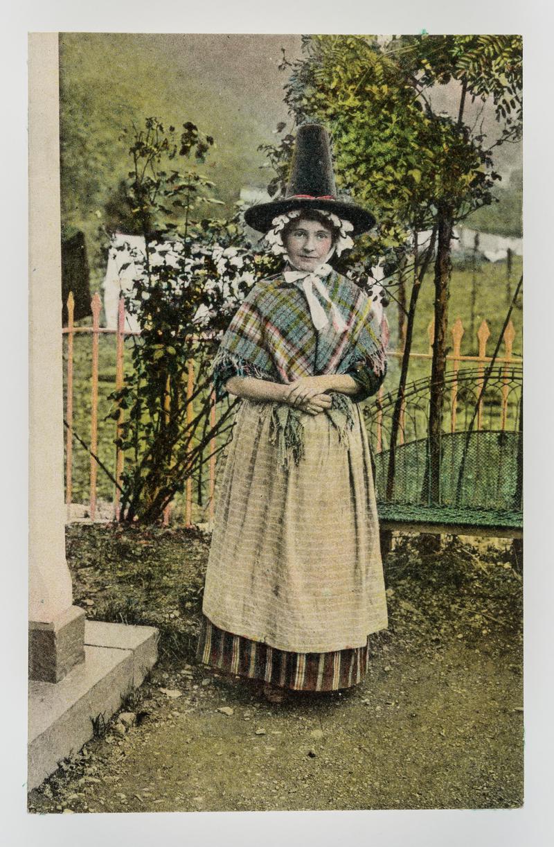 Young lady in Welsh costume standing in garden.