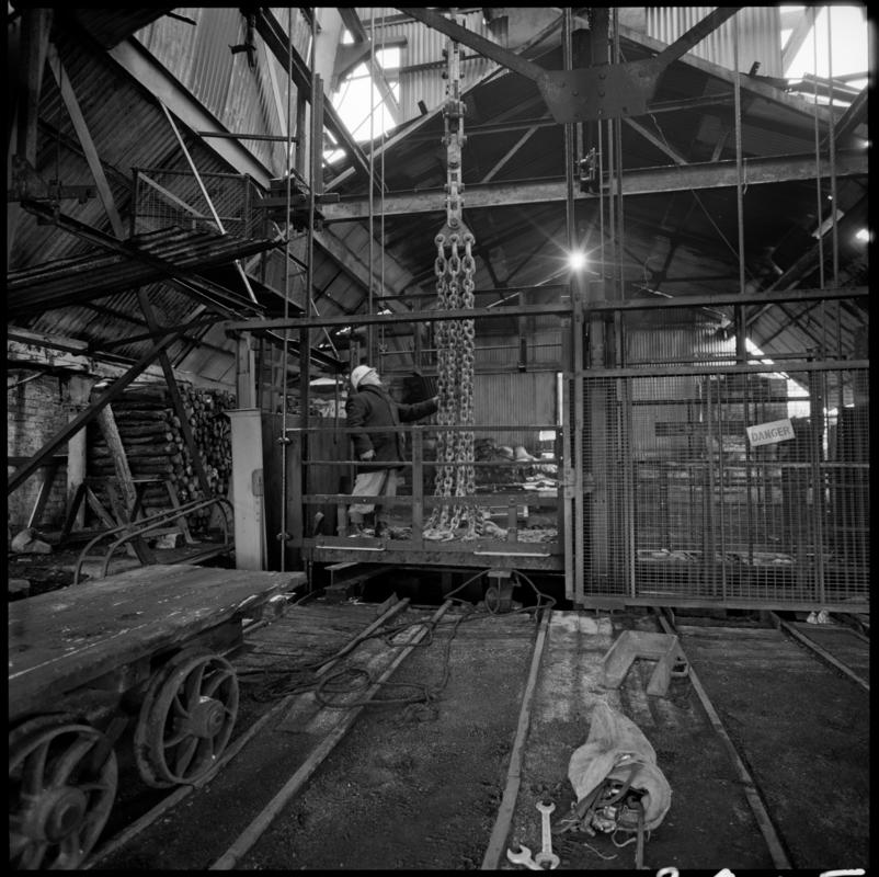 Black and white film negative showing man standing on top of cage at pit top, Big Pit Colliery January 1982.  'Big Pit Blaenavon Jan 1982' is transcribed from original negative bag.