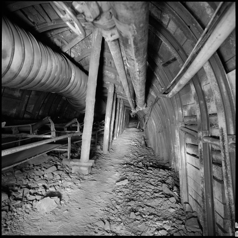 Black and white film negative showing an underground tunnel with high speed conveyor, Merthyr Vale Colliery 2 July 1981.  '2 Jul 1981' is transcribed from original negative bag.