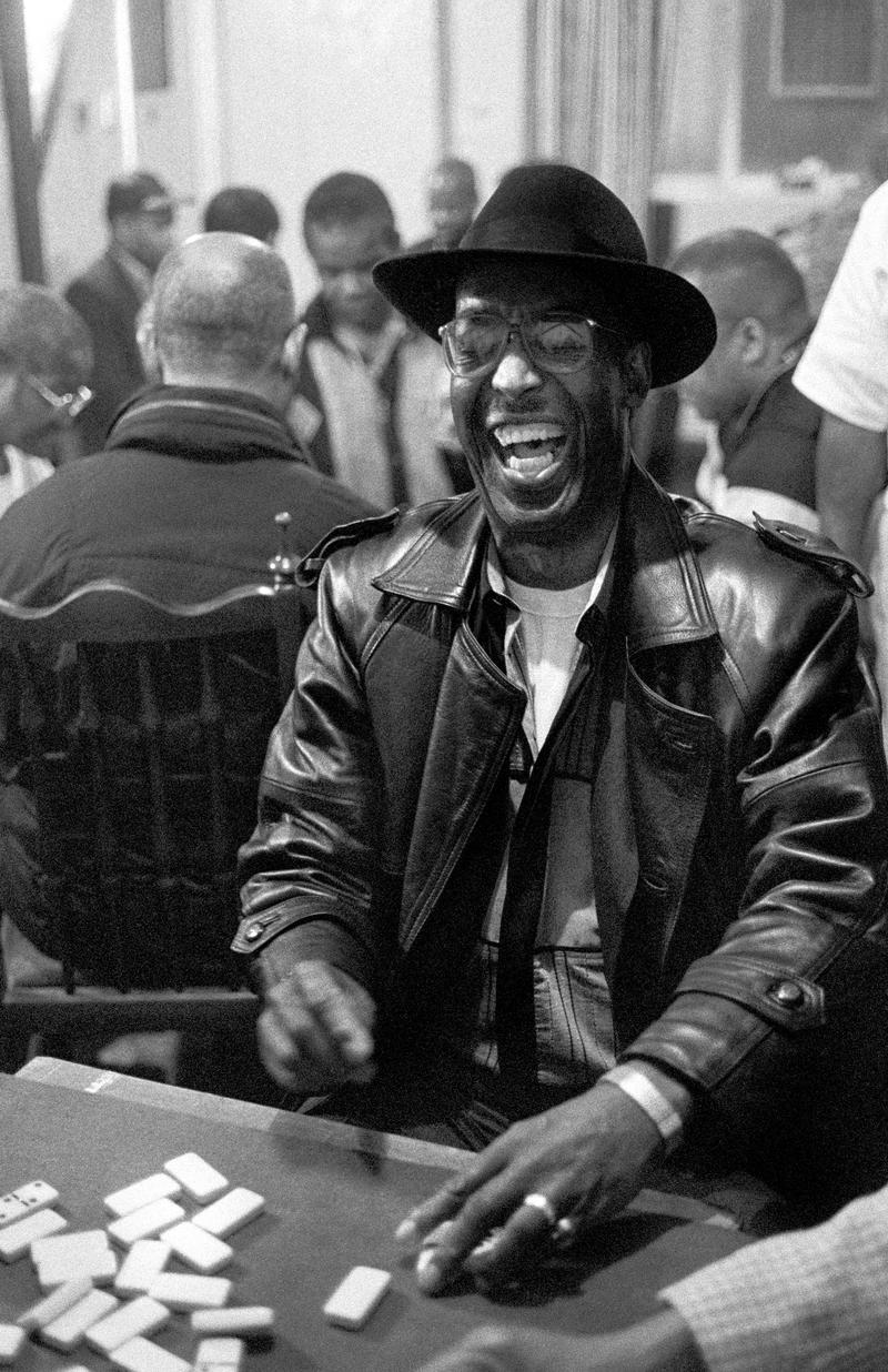 GB. WALES. Cardiff. Butetown - once know as 'Tiger Bay'. Enjoying a winning hand. A player laughing at a dominomatch between Cardiff and London held above Bab's Bistro (now the Caribean Restraurant), West Bute Street.The player was representing the visiting side. 2000