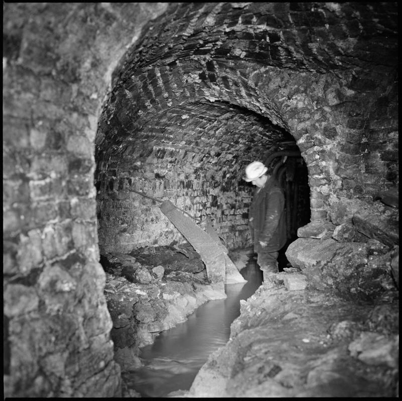Mine official examining a section of a water balance machine cage, near the bottom of the Forge Pit, Blaenavon 1975.