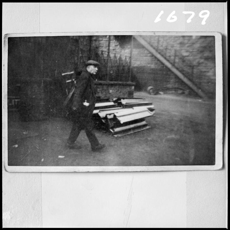 Black and white film negative of a photograph showing a man walking through Deep Navigation Colliery yard.