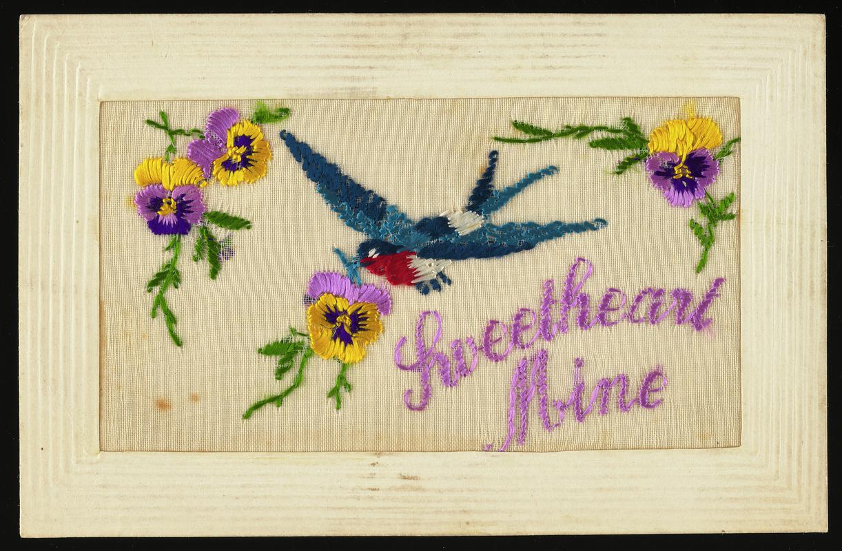 Embroidered silk postcard inscribed Sweetheart Mine. Sent from France by Tom Hardiman to his girlfriend (later wife) Hilda Hobbs during First World War. Undated. Embroidered with bluebird and pink and yellow pansies. Message on back.