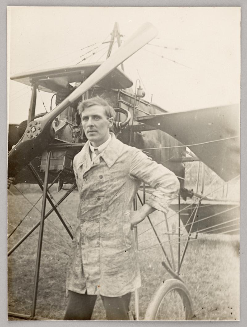View of C.H. Watkins standing infront of aeroplane wearing dirty white coat after working on it.