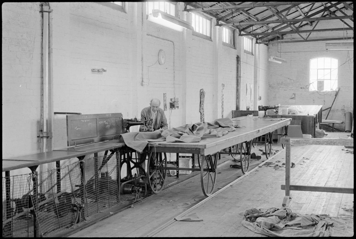 Mr Hopwood machine stitching canvas on one of the sailmaking tables that run on a track at Jenkin Jones and Son sailmakers, 12 Hurman Street, Cardiff Docks.