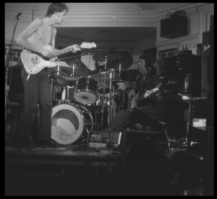 Guitarist and other members of TNT Group on stage. Location unknown.