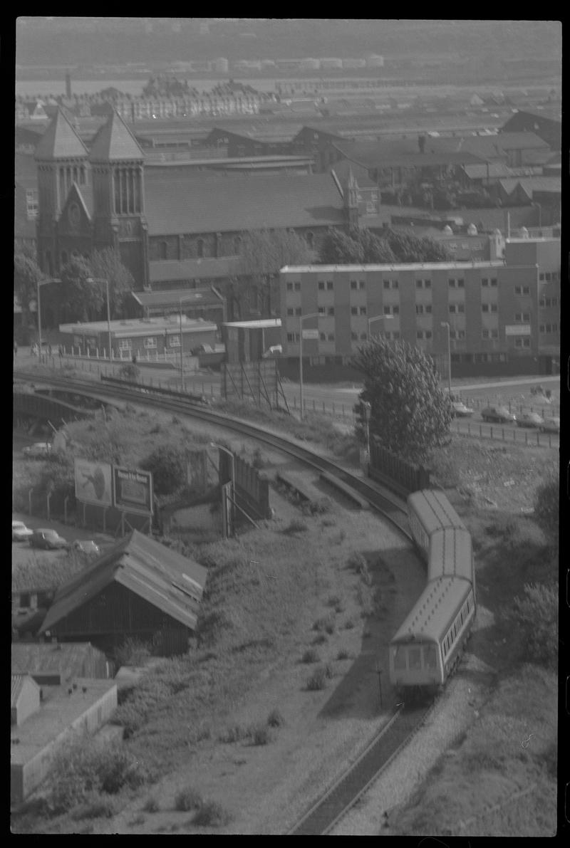 View of Bute Street, with passenger train on a single line to Bute Road in foreground and St Mary's Church in background.