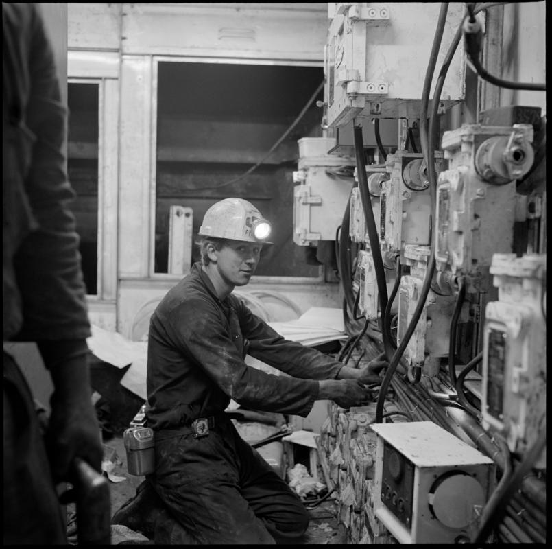Black and white film negative showing an ?engineer carrying out maintenance work, Lady Windsor Colliery.