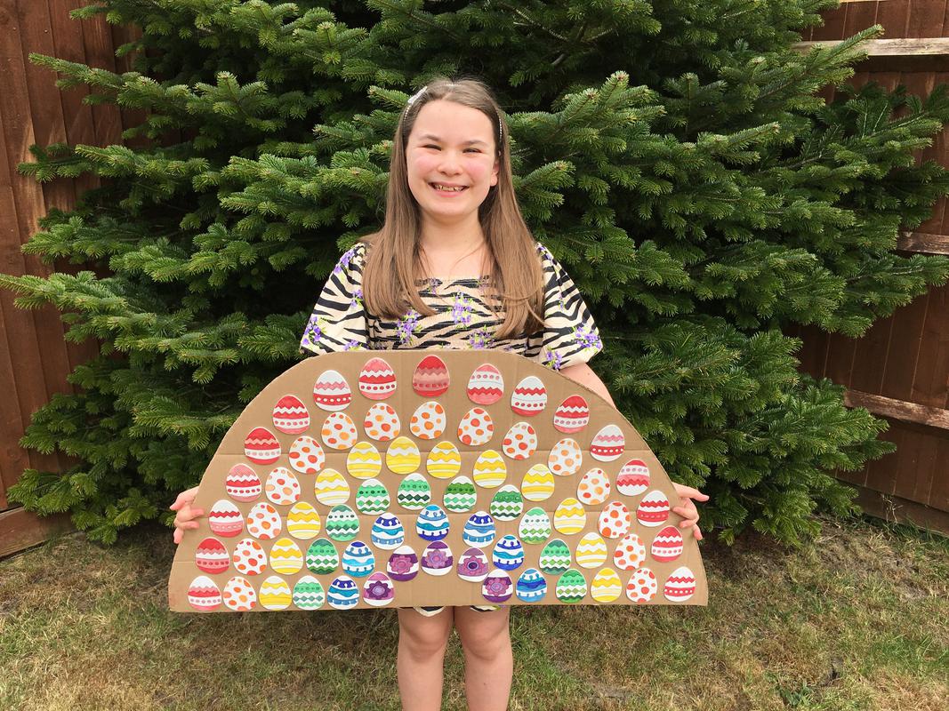 Phoebe Bond holding a rainbow made of Easter eggs.