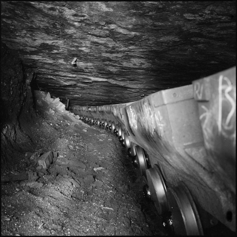 Black and white film negative showing a line of drams in the Graigola Seam, Graig Merthyr Colliery.  Note the unsupported sandstone roof.  'Graig Merthyr' is transcribed from original negative bag.