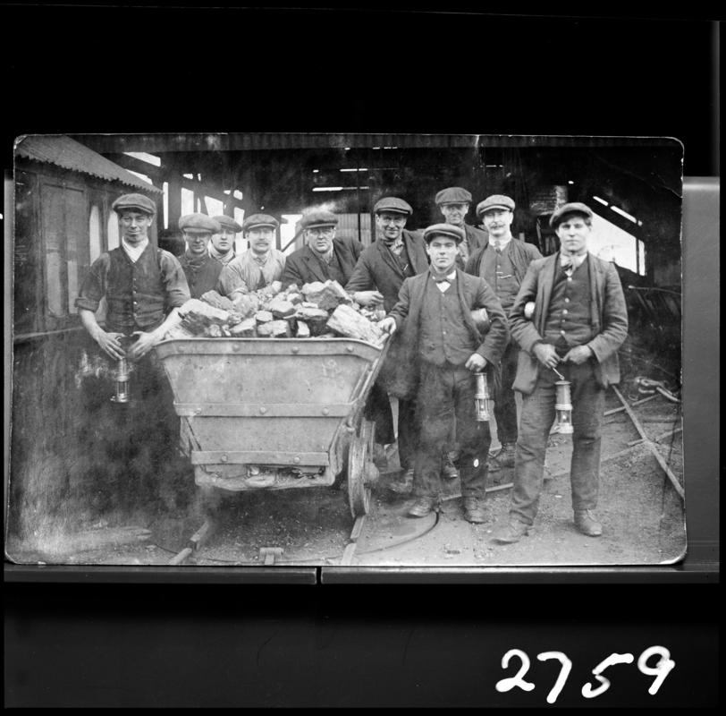 Black and white film negative of a photograph showing a group of miners gathered around a coal dram.  Appears to be identical to 2009.3/2235.