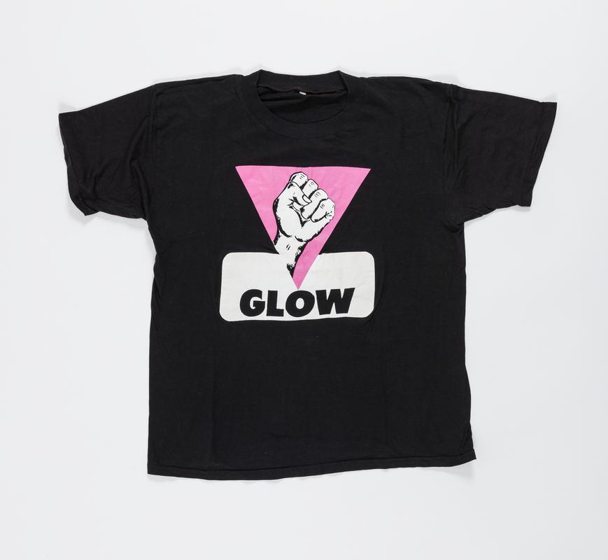 Black t-shirt with a raised fist within a pink triangle and words 'GLOW' on front, and 'SPEAKING FOR OURSELVES' on the back.