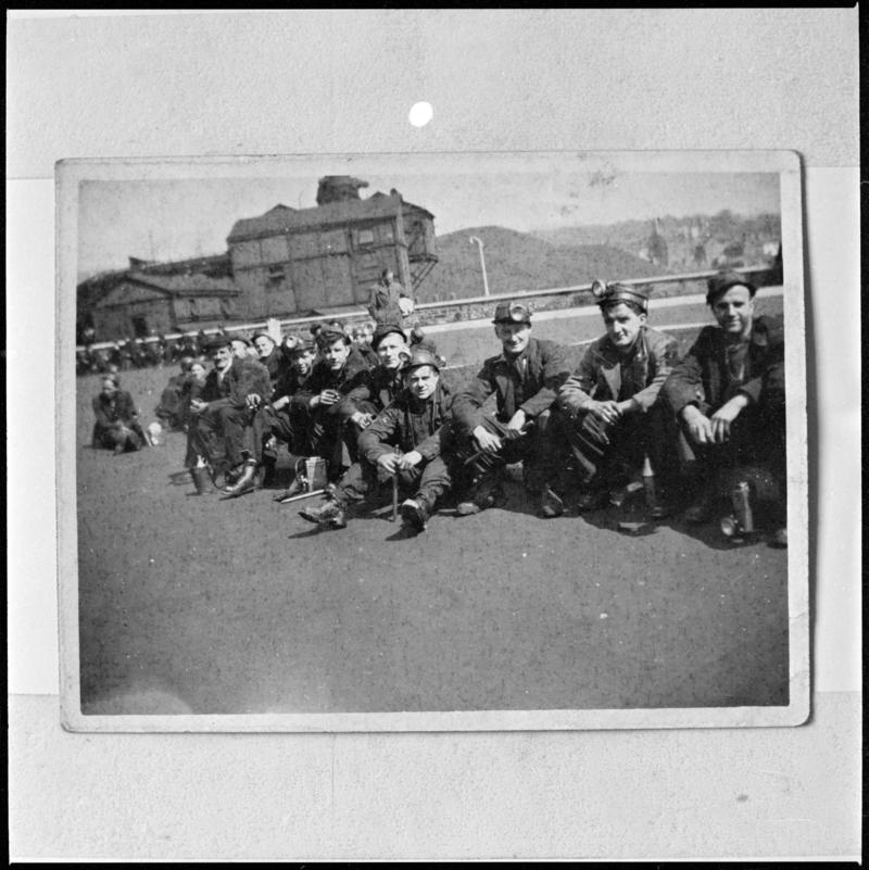 Black and white film negative of a photograph showing a group of miners sat on the ground, Deep Navigation Colliery.  'Deep Navigation' is transcribed from original negative bag.