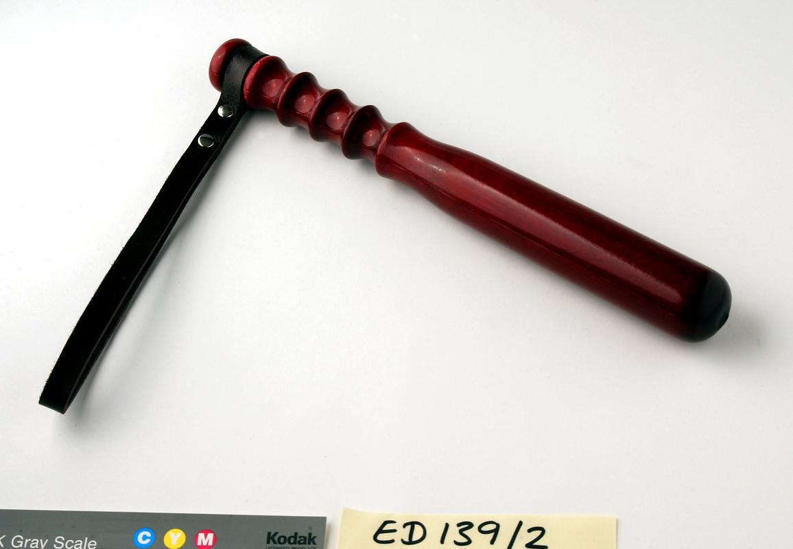 Red finish wooden police truncheon with leather wrist strap.