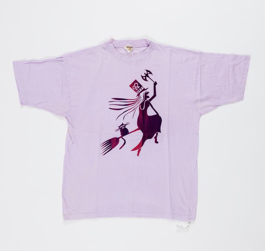 Pale purple t-shirt with design of a witch and a cat. The witch has the double womens symbol on her hat, and carries a labrys.