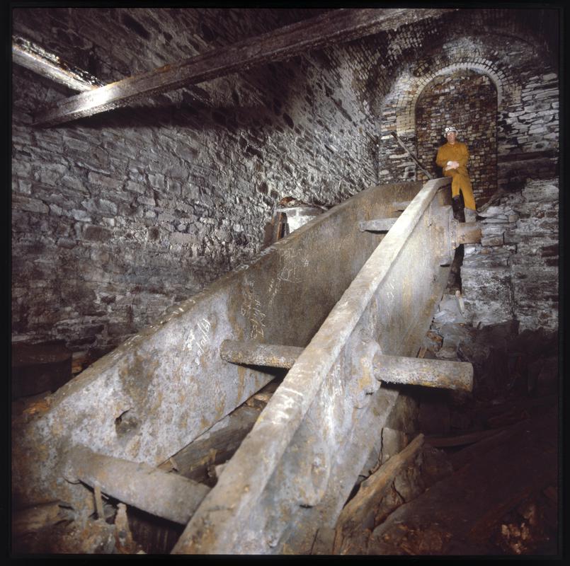 Shaftsman and the cast iron beam of a Cornish pumping engine made by Harvey of Hayle in 1858. It was situated in a large chamber half way down the No.2 shaft, Penrhiwceiber Colliery.