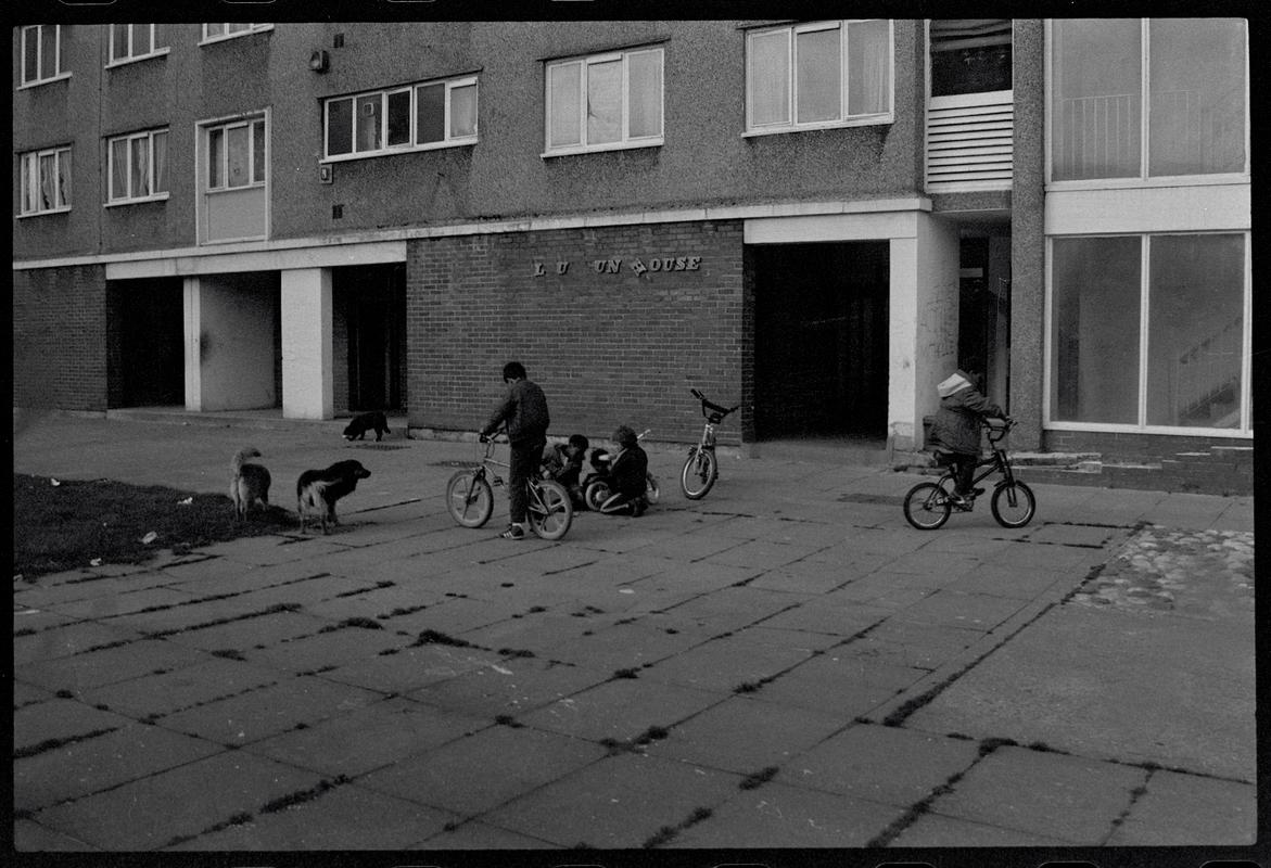 Children playing on bikes outside flats, Butetown.