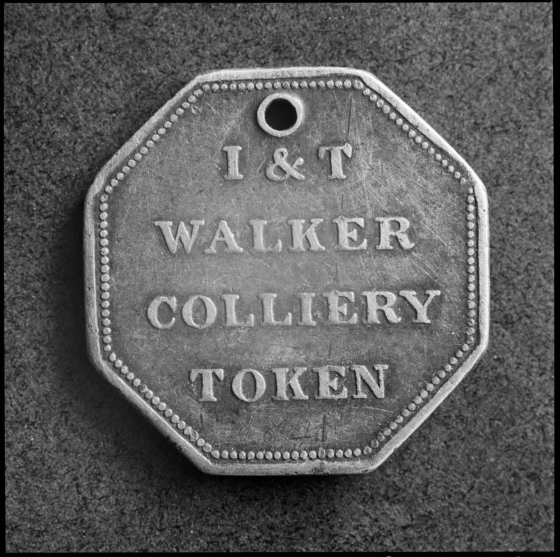 Black and white film negative showing an I & T Walker Colliery Token.