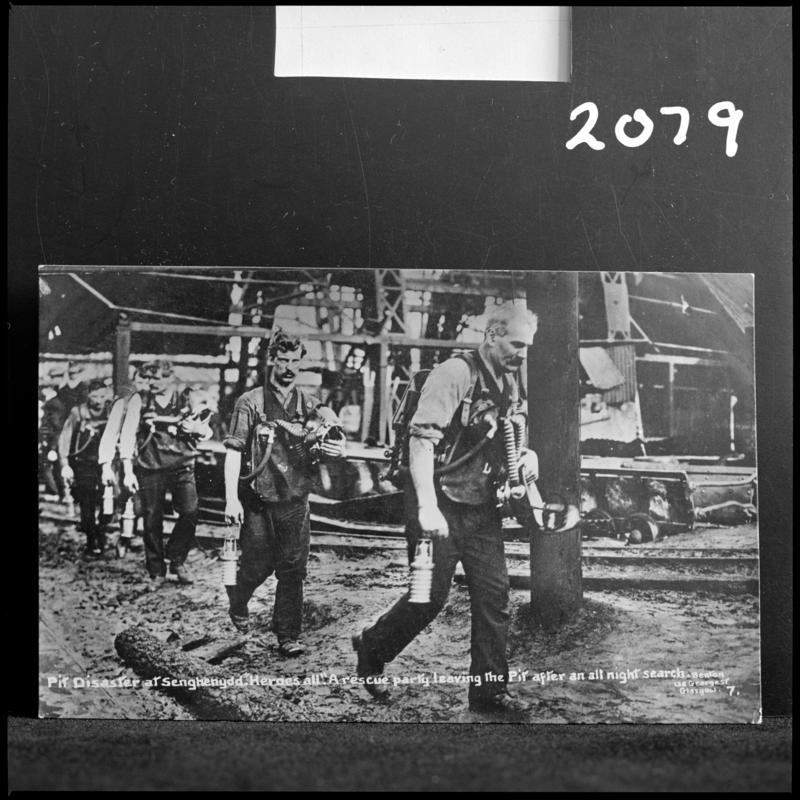 Black and white film negative of a photograph showing the scene at Universal Colliery, Senghenydd after the explosion of 14 October 1913.  Caption on photograph reads 'Pit Disaster at Senghenydd.  A rescue party leaving the Pit after an all night search'.