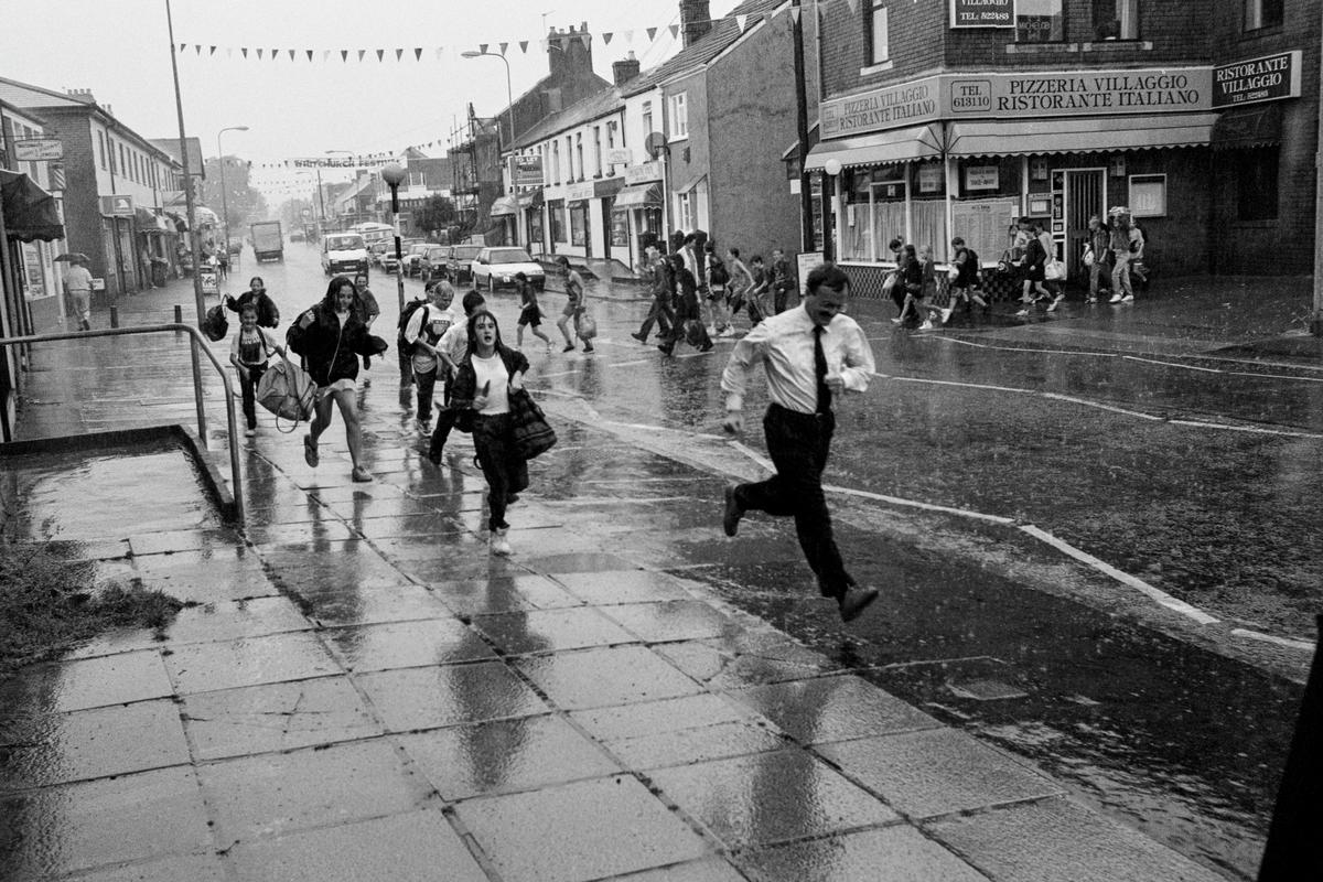 GB. WALES. Cardiff. Running from rain in Whitchurch. 1995.
