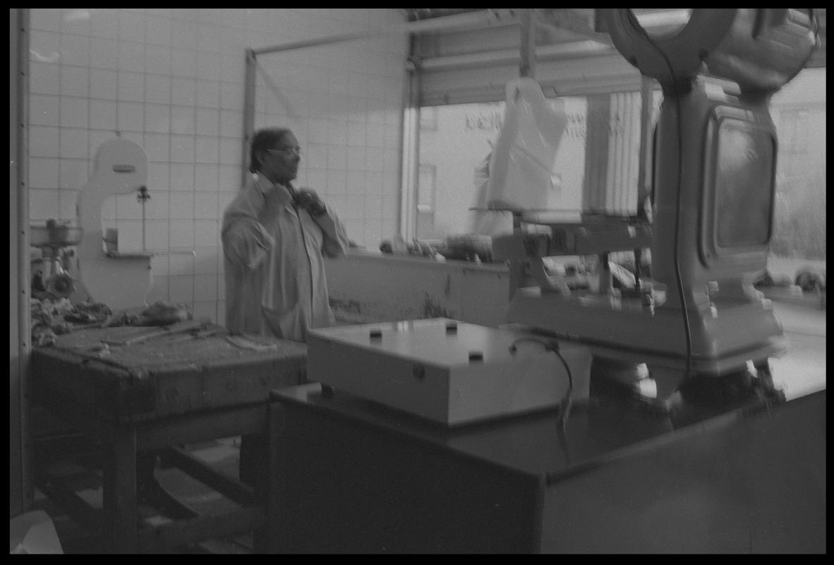 Butcher behind counter of his shop, Loudoun Square, Butetown.