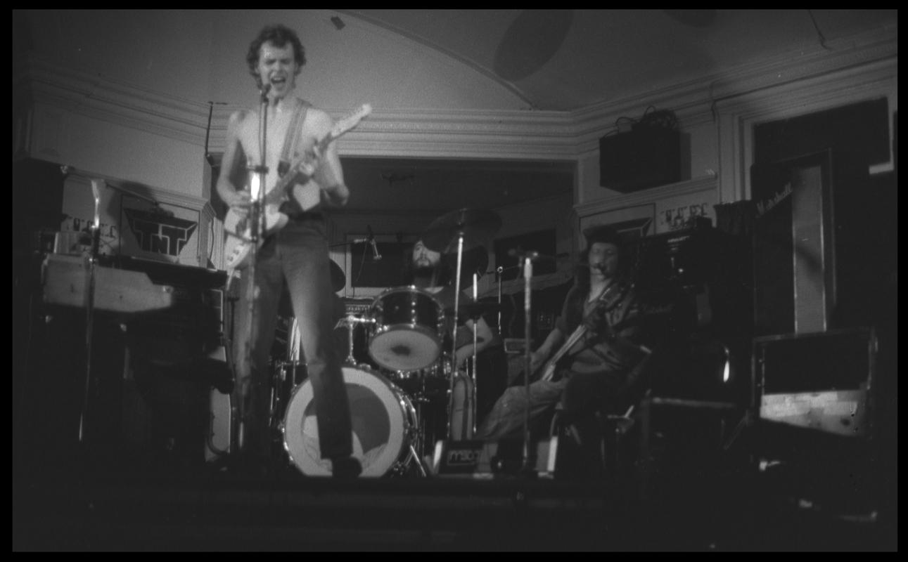 Guitarist and other members of TNT Group on stage. Location unknown.