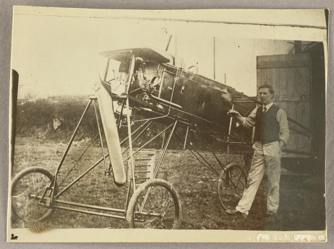 Photograph of Watkins monoplane showing tricycle undercarriage. C.H. Watkins standing at side.