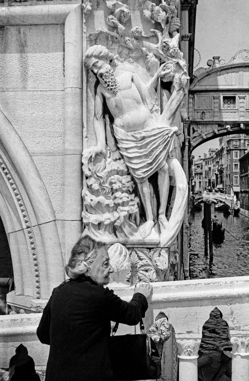 ITALY. Venice. Elderly lady on a Venice bridge with the Bridge of Sighs in the background. 1964.
