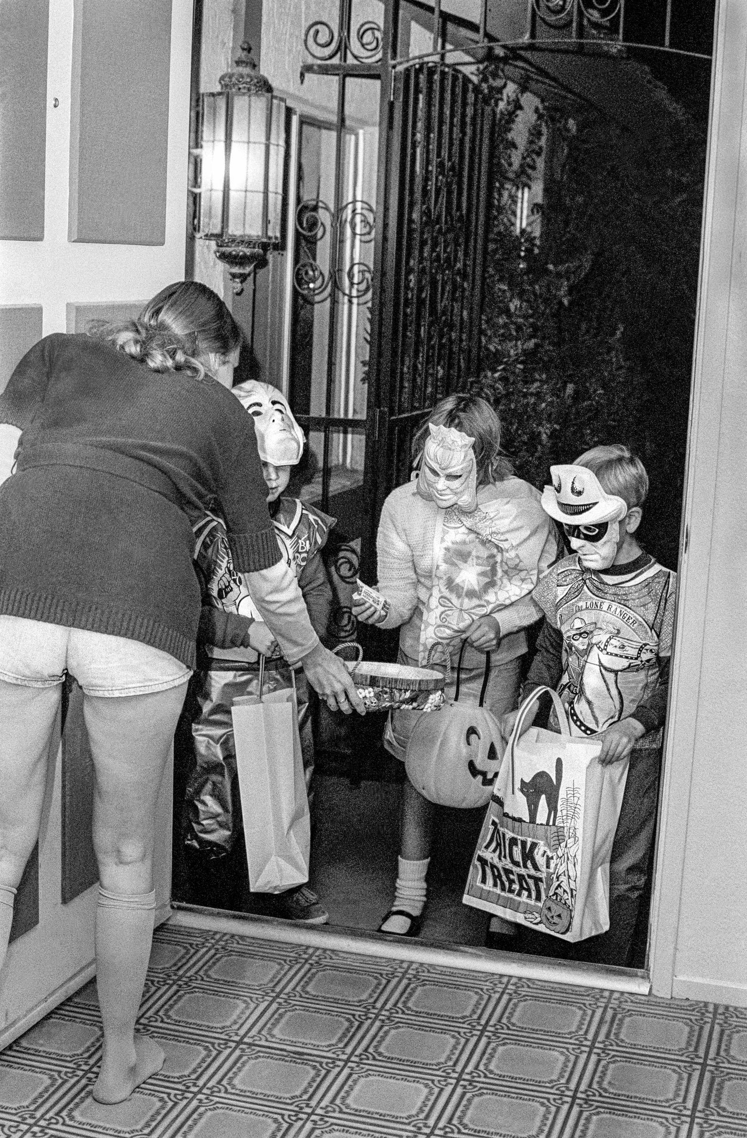 Three youths dressed in typical fancy dress go round the local houses for the traditional Trick or Treat. Tempe, Arizona USA