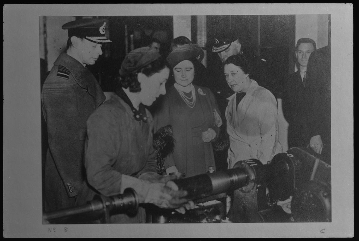 Film negative of a photograph showing visit of King George VI and Queen Elizabeth to Currans, Butetown during World War II. King and Queen inspecting the manufacture of a shell.