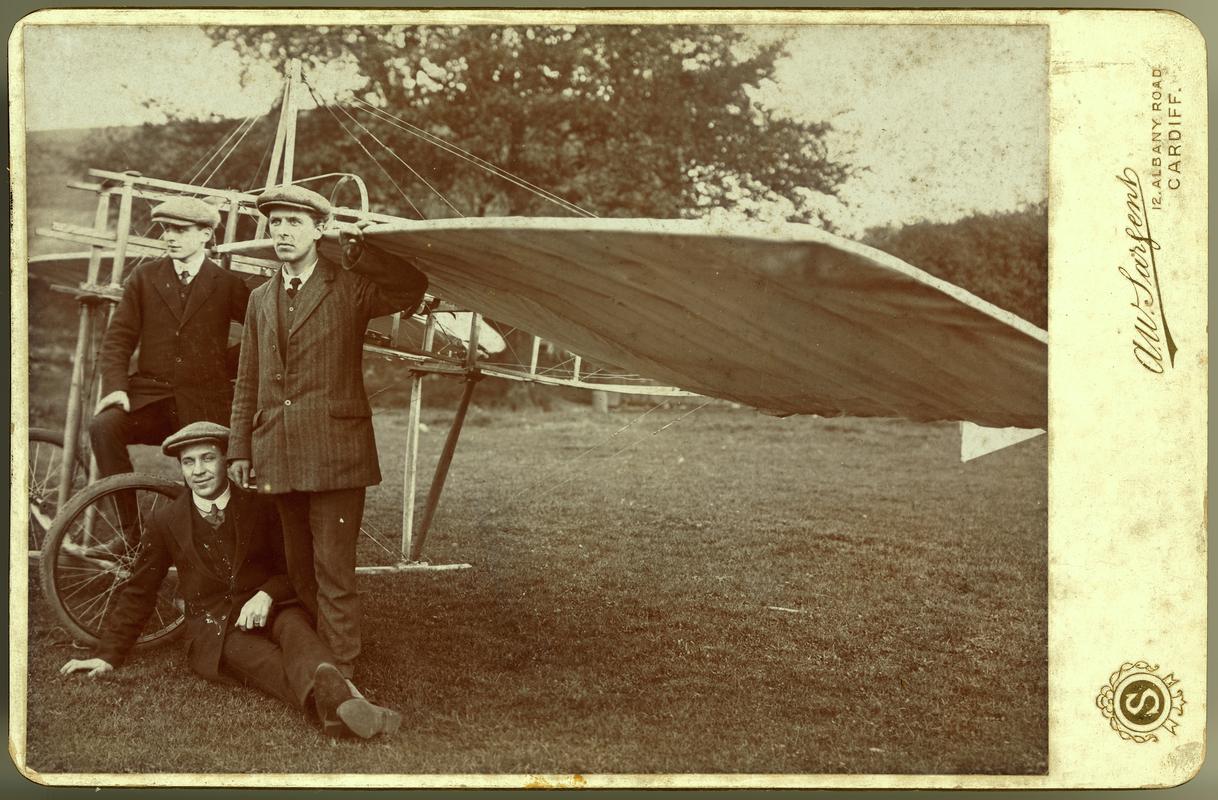 Charles Horace Watkins standing beside his monoplane Robin Gôch with two other men.