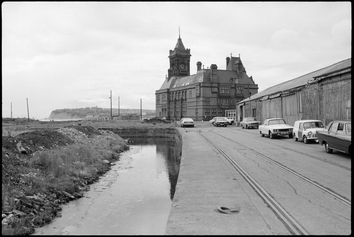 Strip of water at the edge of the filled in Bute East Dock basin, with Pierhead building and Penarth head in the background.