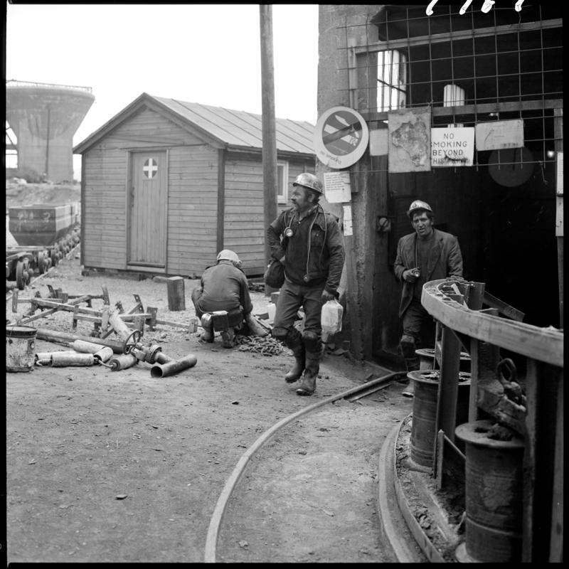 Black and white film negative showing men arriving back on the surface after their shift, Big Pit 1979.
