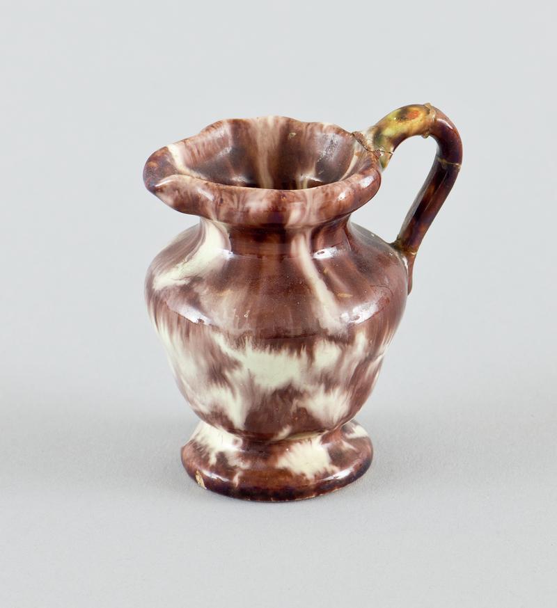 China jug. Small brown and cream glazed jug with chip on base.