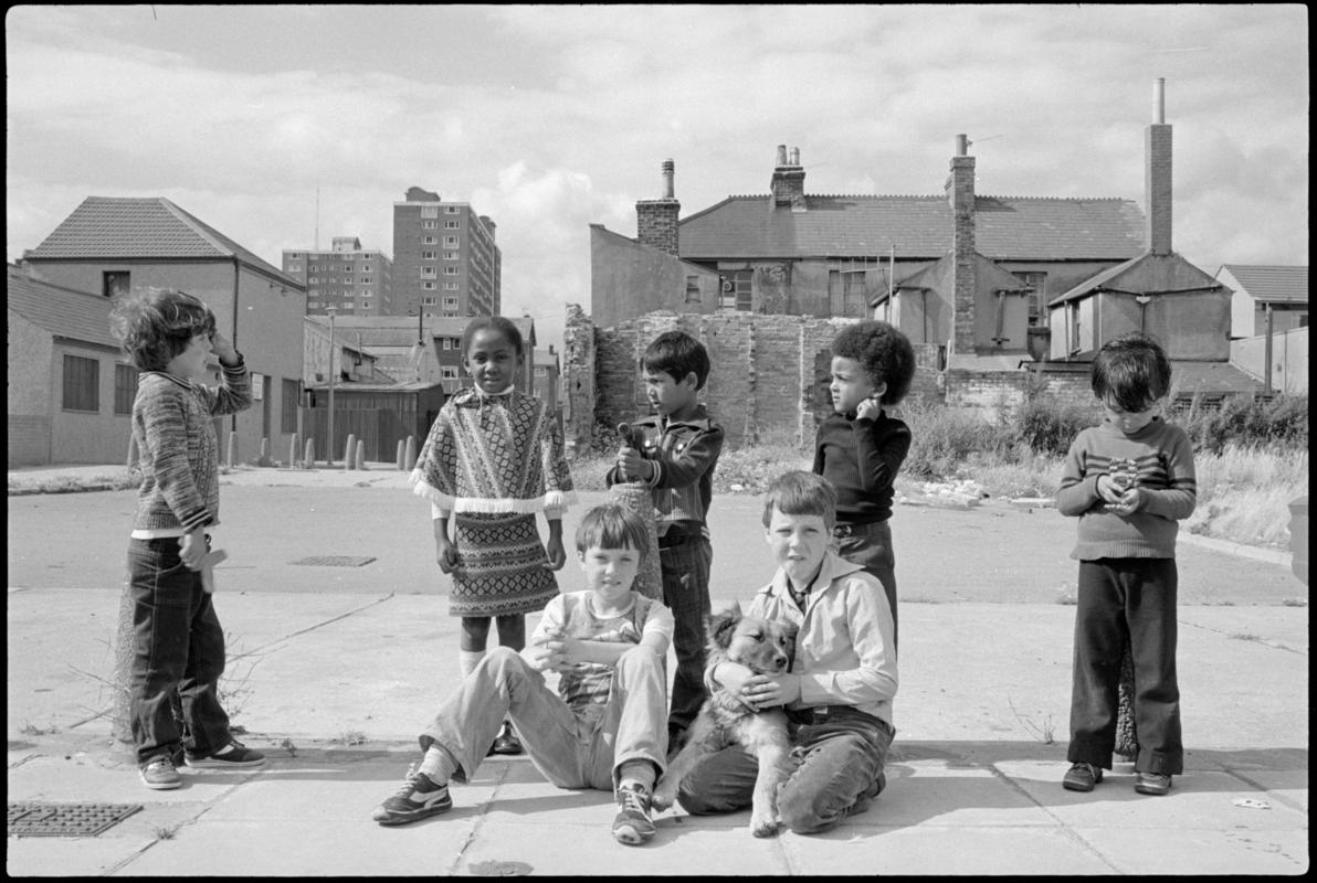 Group of children and dog in Butetown. In the background are new and derelict housing, including Loudoun Square flats.