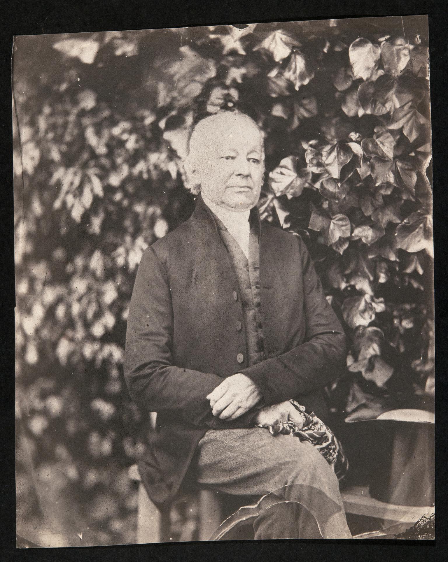 Gentleman seated in garden, photograph