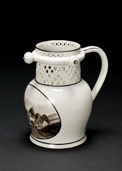 Jug with a cut out trellis-like design of circles and lozenges at the top, with a ring around neck from which protrude three bulbous spouts. 