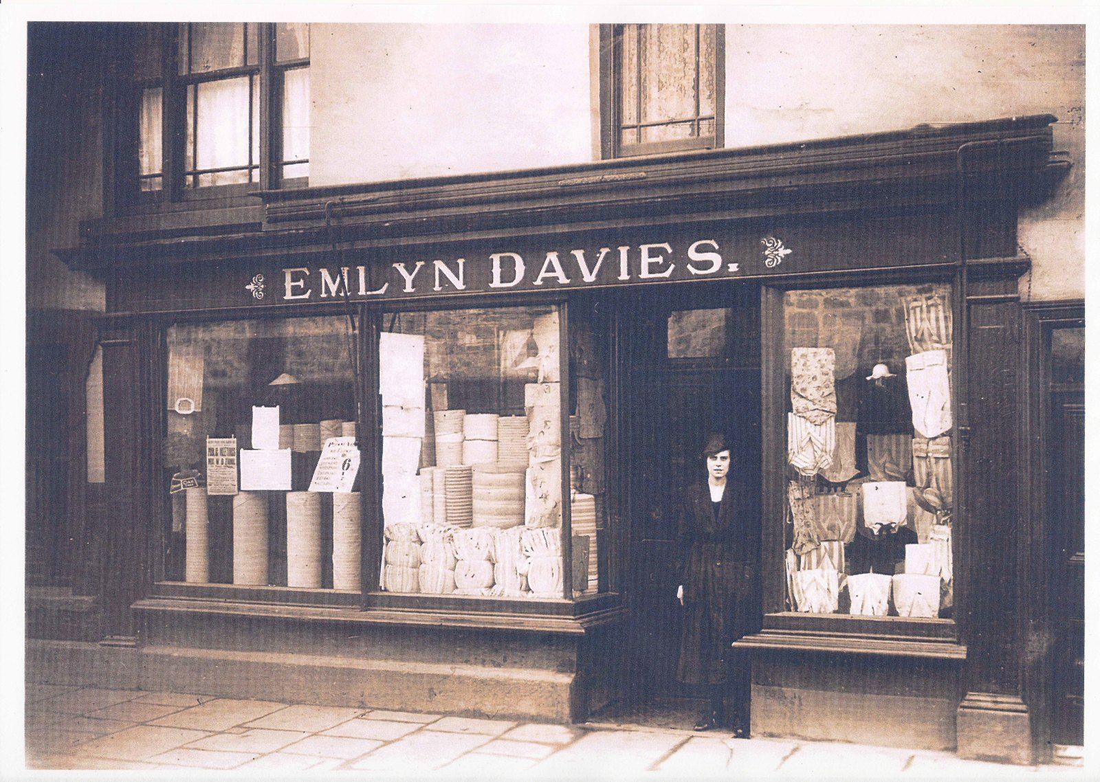 Miriam Davies o flaen siop ddillad ei thad ar East Street, Dowlais tua 1917
