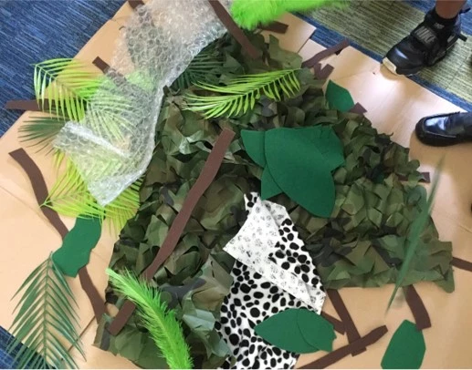 Llun o "nyth deinosor" wedi'i wneud o ffabrig, bubble wrap a dail plastig